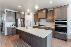 Kitchen featuring light hardwood / wood-style flooring, appliances with stainless steel finishes, sink, and backsplash