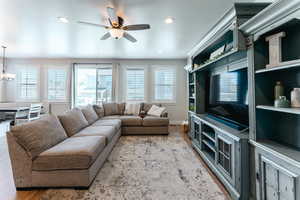 Living room featuring light wood-type flooring and ceiling fan with notable chandelier