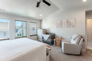 Carpeted bedroom featuring multiple windows, lofted ceiling, and ceiling fan