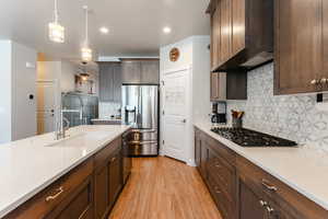 Kitchen featuring light hardwood / wood-style flooring, stainless steel appliances, hanging light fixtures, and sink