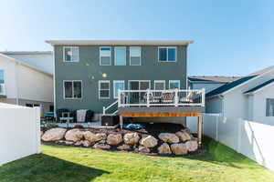 Back of house with a wooden deck, a yard, and a patio