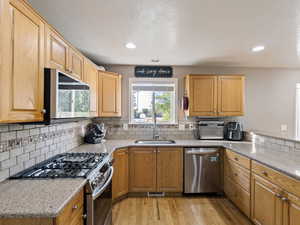 Kitchen with hardwood flooring, stainless steel appliances, and granite countertops