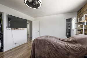 Main bedroom with light LVP flooring, wooden walls, and main bathroom connected.