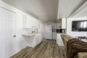 Kitchen featuring  white appliances, sink, and white cabinets