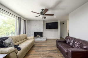 Living room featuring ceiling fan, a stone fireplace, and LVP flooring