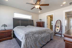 Carpeted bedroom with connected bathroom and ceiling fan