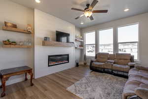 Living room with light hardwood / wood-style floors, a large fireplace, plenty of natural light, and ceiling fan