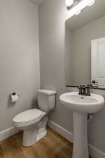 Bathroom featuring toilet, hardwood / wood-style flooring, and sink