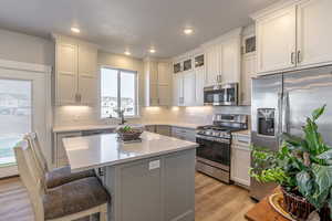 Kitchen featuring tasteful backsplash, a center island, a breakfast bar area, stainless steel appliances, and light hardwood / wood-style flooring