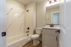 Full bathroom with vanity, bathtub / shower combination, wood-type flooring, and toilet