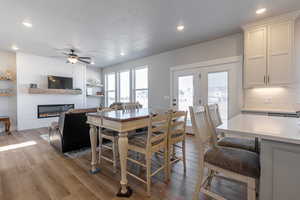 Dining area with a large fireplace, light wood-type flooring, and ceiling fan