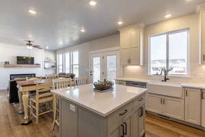 Kitchen with light hardwood / wood-style floors, sink, a fireplace, and a kitchen island