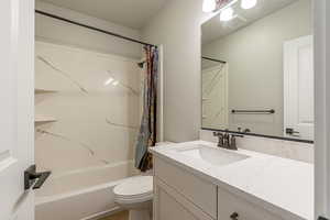 Full bathroom featuring vanity, toilet, and shower / bathtub combination with curtain