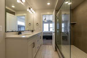 Bathroom featuring vanity, a tile shower, and ceiling fan