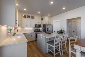 Kitchen featuring light hardwood / wood-style floors, white cabinetry, stainless steel appliances, and a kitchen island