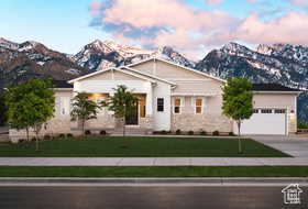 View of front of property featuring a mountain view, a garage, and a front lawn