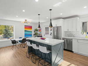 Kitchen featuring a center island, appliances with stainless steel finishes, pendant lighting, and white cabinetry