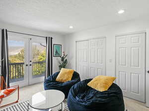 Bedroom with french doors, light carpet, access to exterior, and a textured ceiling