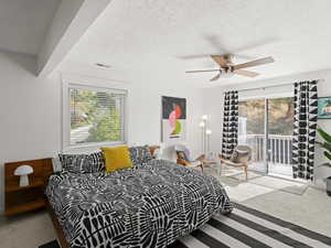 Primary bedroom featuring a textured ceiling, multiple windows, access to outside deck, and ceiling fan