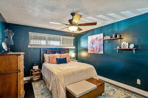 Bedroom with a textured ceiling, hardwood / wood-style floors, and ceiling fan