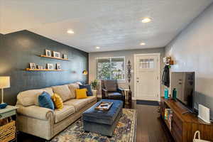 Living room with a textured ceiling and dark hardwood / wood-style floors