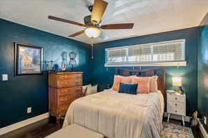 Bedroom with ceiling fan, a textured ceiling, and dark hardwood / wood-style flooring