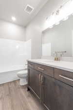 Full bathroom with shower / tub combination, vanity, toilet, and hardwood / wood-style floors