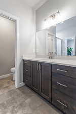 Bathroom featuring vanity, a shower with shower door, and toilet