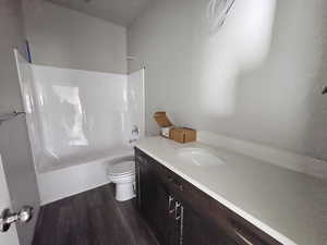 Full bathroom featuring toilet, hardwood / wood-style flooring, vanity, and washtub / shower combination