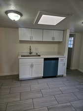 Kitchen featuring white cabinets, stainless steel dishwasher, sink, and a textured ceiling