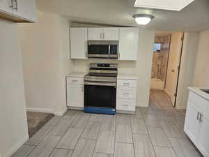 Kitchen featuring appliances with stainless steel finishes, a textured ceiling, and white cabinets