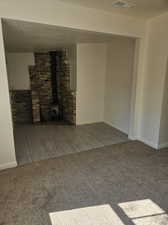 Unfurnished living room with carpet floors and a wood stove