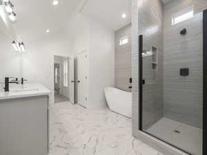 Master Bathroom with vanity, independent shower and bath, lofted ceiling, and plenty of natural light