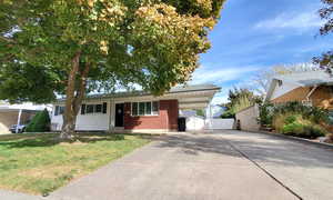 Ranch-style home featuring a front lawn and a carport