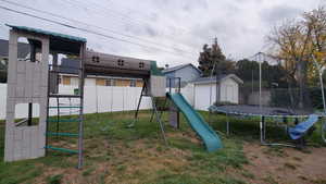 View of play area with a storage unit, a yard, and a trampoline