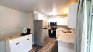 Kitchen with white cabinetry, appliances with stainless steel finishes, sink, and LVP flooring