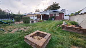 View of yard featuring a patio area, an outdoor fire pit, and a trampoline