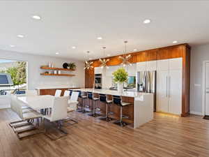 Kitchen featuring an island with sink, a breakfast bar area, and hanging light fixtures