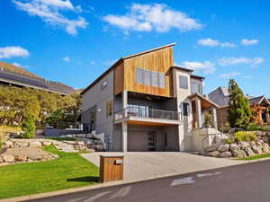 Contemporary home with a front lawn, a garage, and a balcony