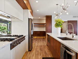 Kitchen with sink, hanging light fixtures, stainless steel appliances, white cabinets,.