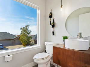 Bathroom with toilet, vanity, and a wealth of natural light