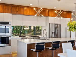 Kitchen with appliances with stainless steel finishes, white cabinetry, decorative light fixtures, and sink