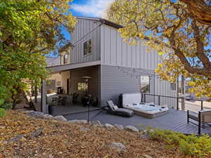 Back of house featuring a patio, a deck, and an outdoor hot tub