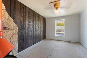 Empty room featuring ceiling fan and wood walls