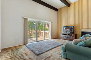 Living room featuring high vaulted ceiling, beamed ceiling, and wood walls