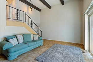 Living room featuring a high ceiling, beam ceiling, and carpet flooring