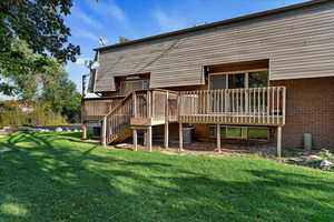 Back of house featuring a wooden deck, a lawn, and central AC