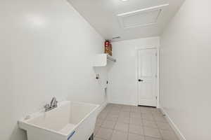 Laundry room with washer hookup, hookup for an electric dryer, sink, light tile patterned floors, and a textured ceiling