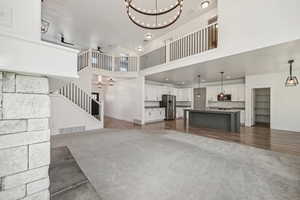 Unfurnished living room featuring a notable chandelier, a towering ceiling, and dark hardwood / wood-style flooring