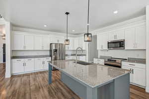 Kitchen featuring sink, white cabinetry, stainless steel appliances, pendant lighting, and dark hardwood / wood-style floors